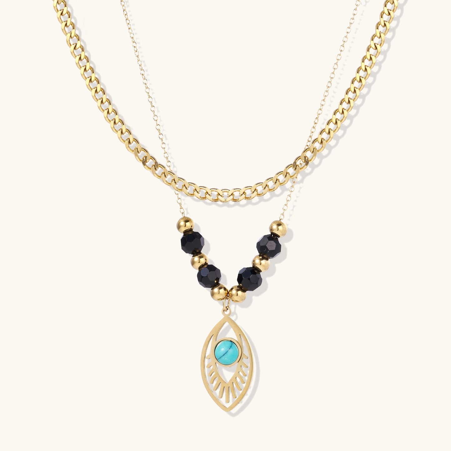 Gold layered necklace set with evil eye pendant, turquoise center stone, and black beaded chain on cream background