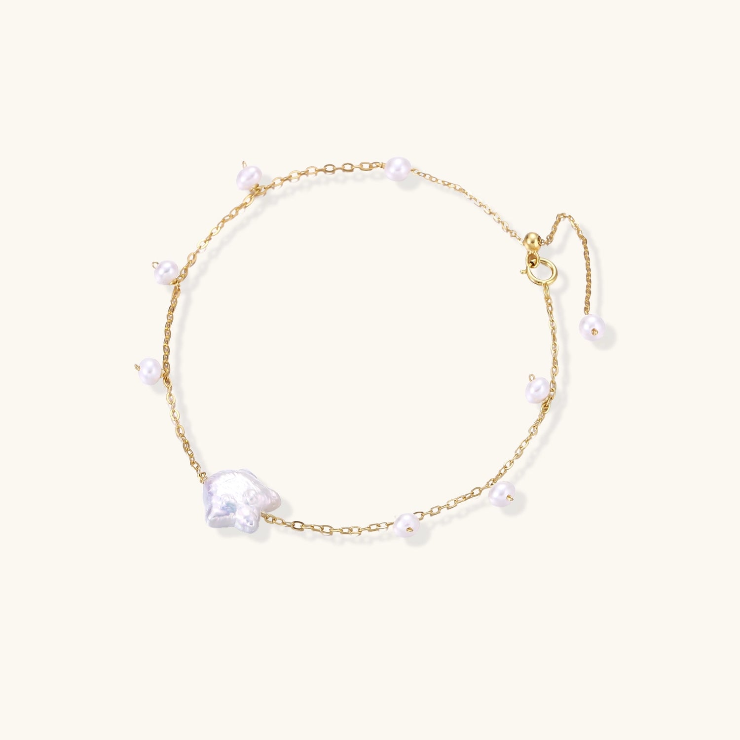 Delicate 18K gold-plated silver chain bracelet with freshwater and baroque pearls on cream background