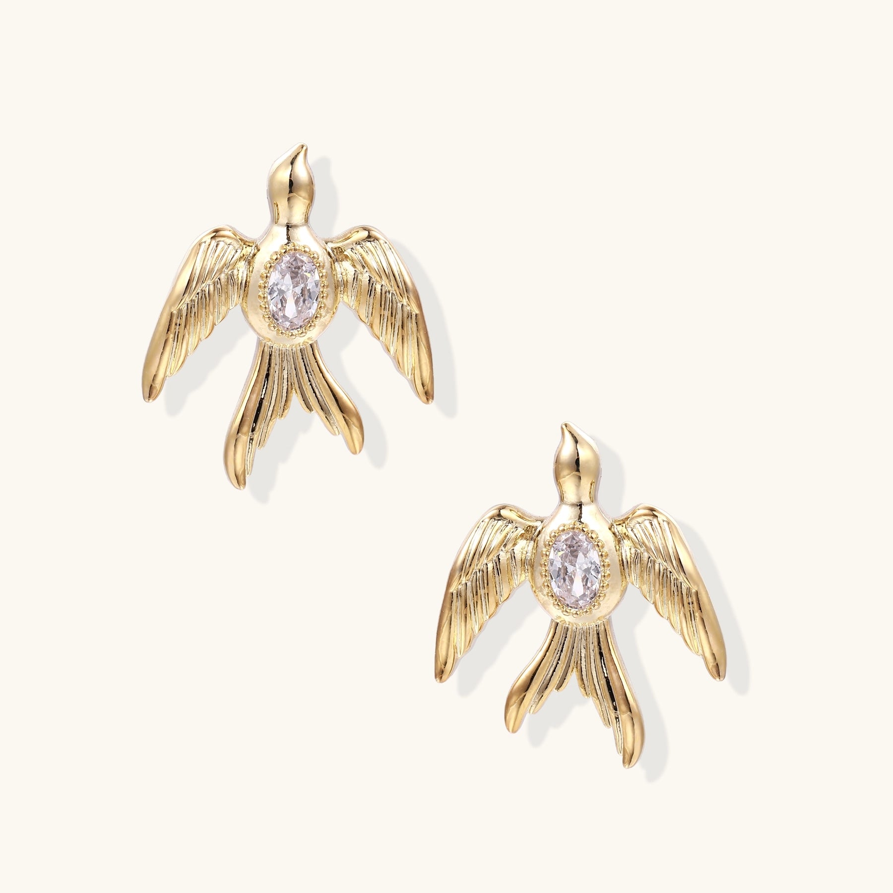 Pair of gold-plated eagle stud earrings with spread wings and purple zirconia center stones on white background.