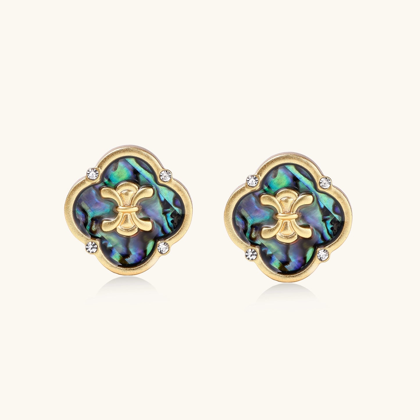 Gold-plated quatrefoil stud earrings featuring iridescent abalone shell centers with decorative motifs and crystal accents