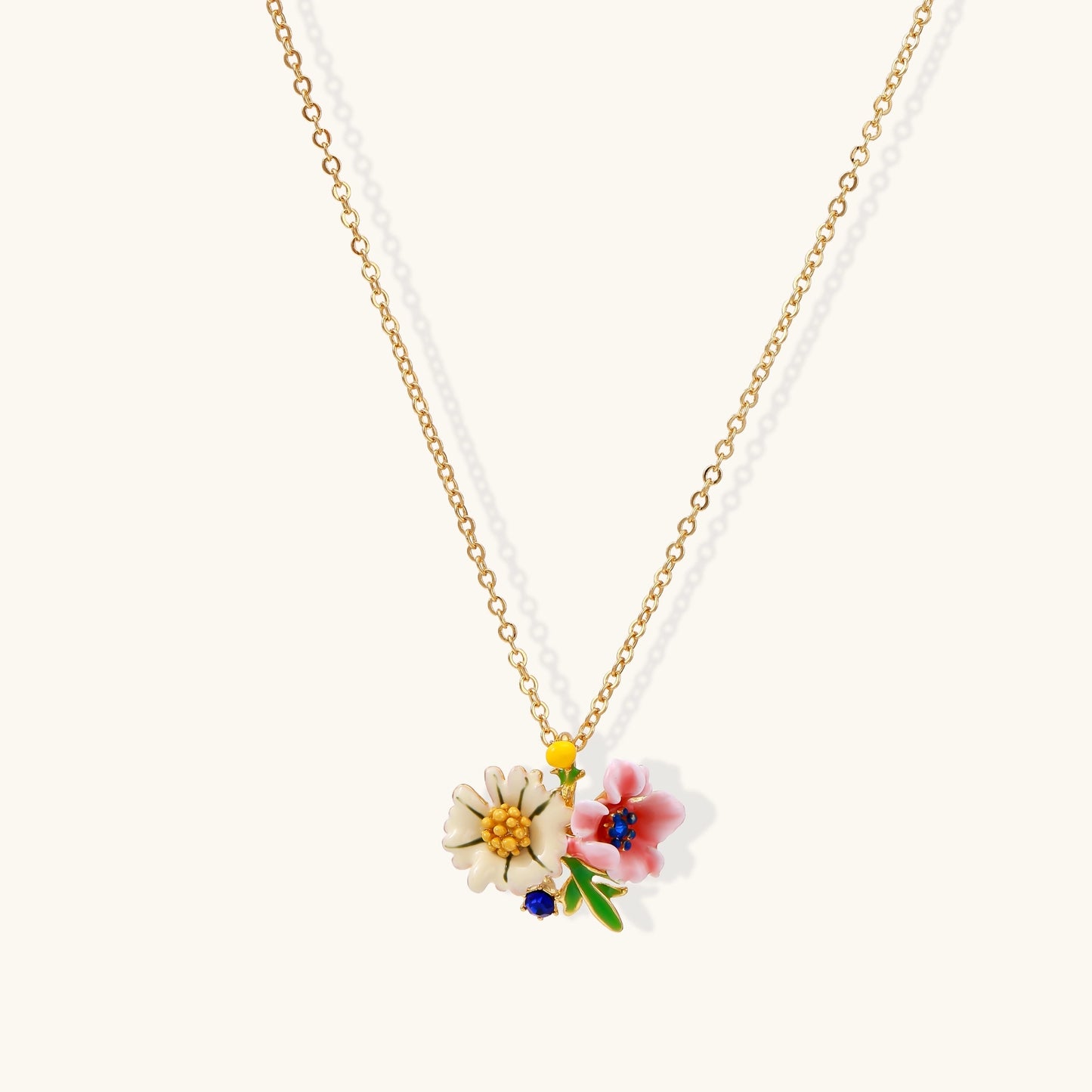 Delicate gold-plated necklace featuring white daisy and pink flower enamel pendant with colorful accents on white background.