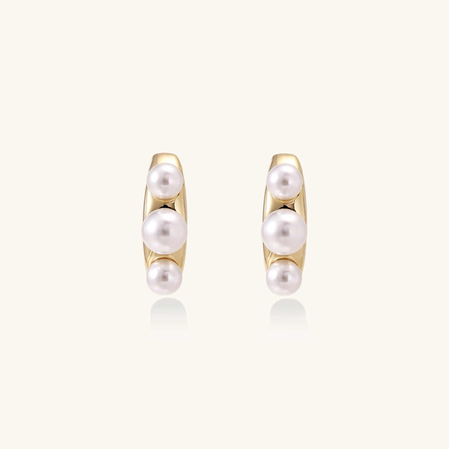 Delicate gold stud earrings with three lustrous white freshwater pearls arranged in an organic curved line.