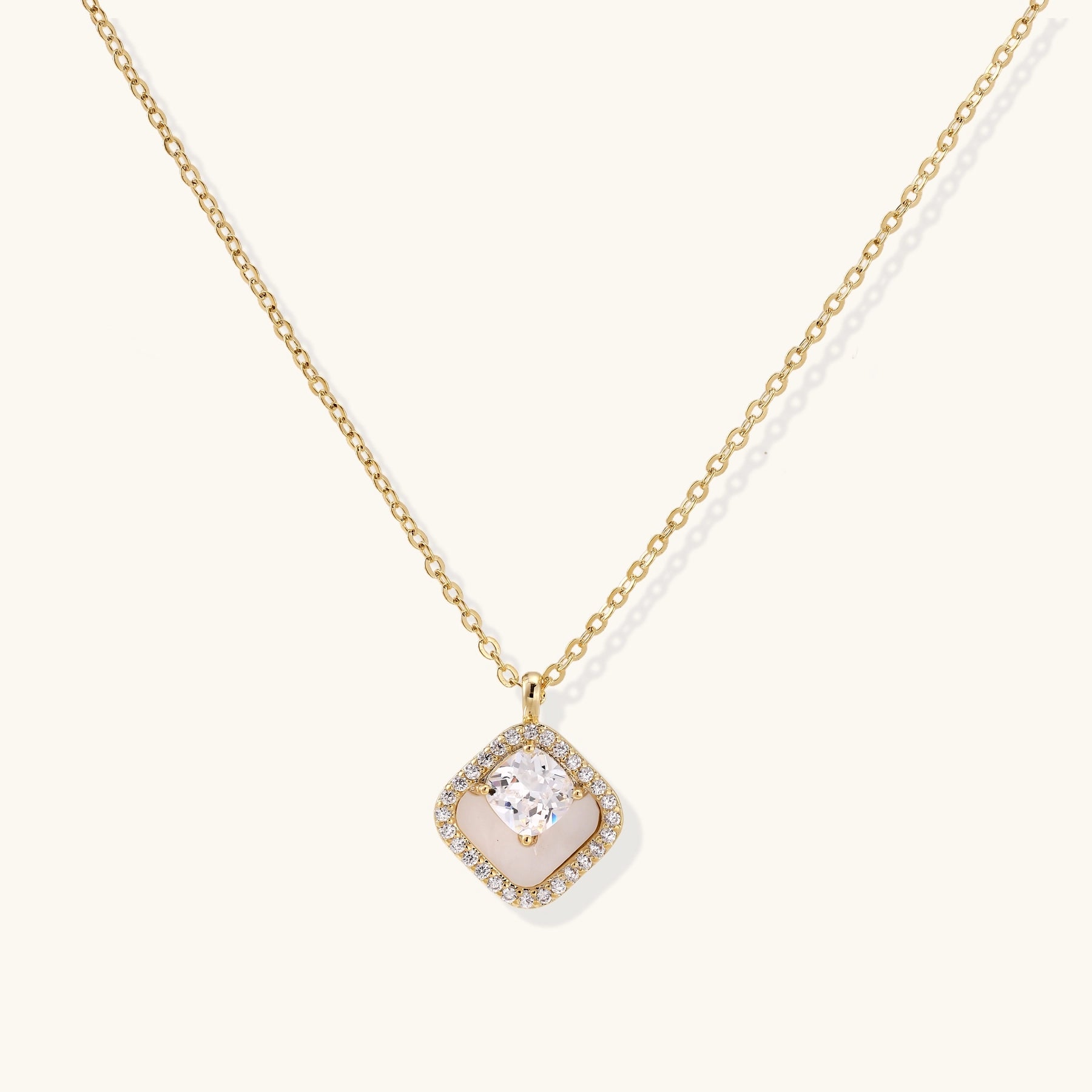 Gold-plated necklace with cushion-shaped pendant featuring a freshwater pearl surrounded by crystal halo on white background.